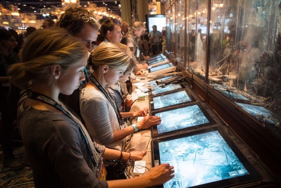 Visitors use a row of interactive exhibit touchscreens