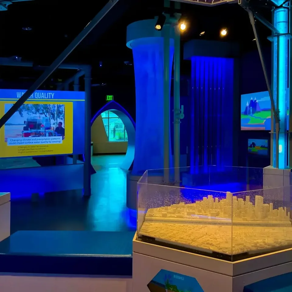 The Fate of Rain exhibit with illuminated rain tubes, clouds and a model of the local landscape