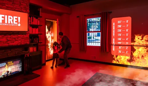 Visitors explore a projected fire scenario inside Fire! Science & Safety at California Science Center