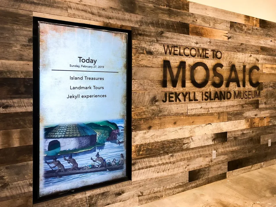 A vertical Mosaic welcome display against the timber wall at the Jekyll Island Museum