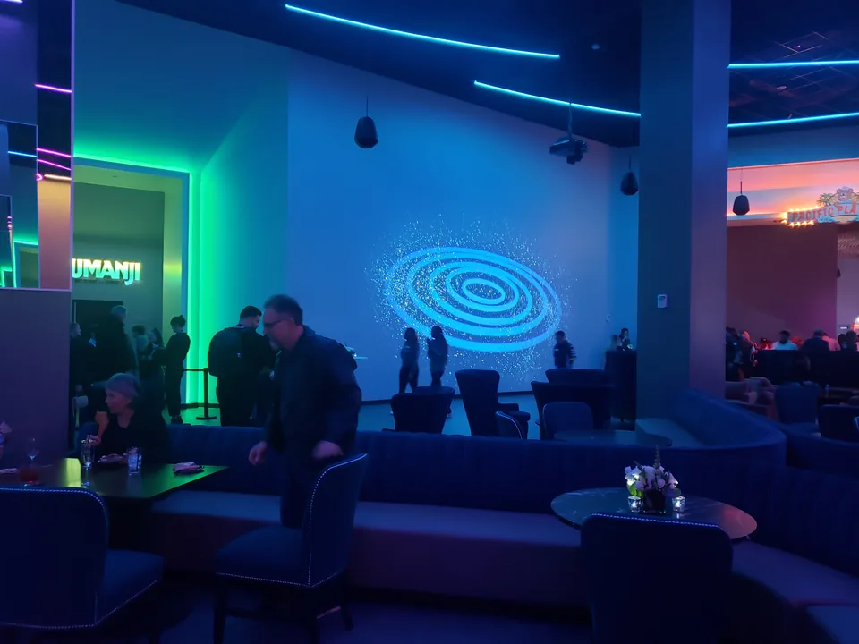 Guests in Sony Wonderverse’s lounge beside a large portal projection and suspended loudspeakers